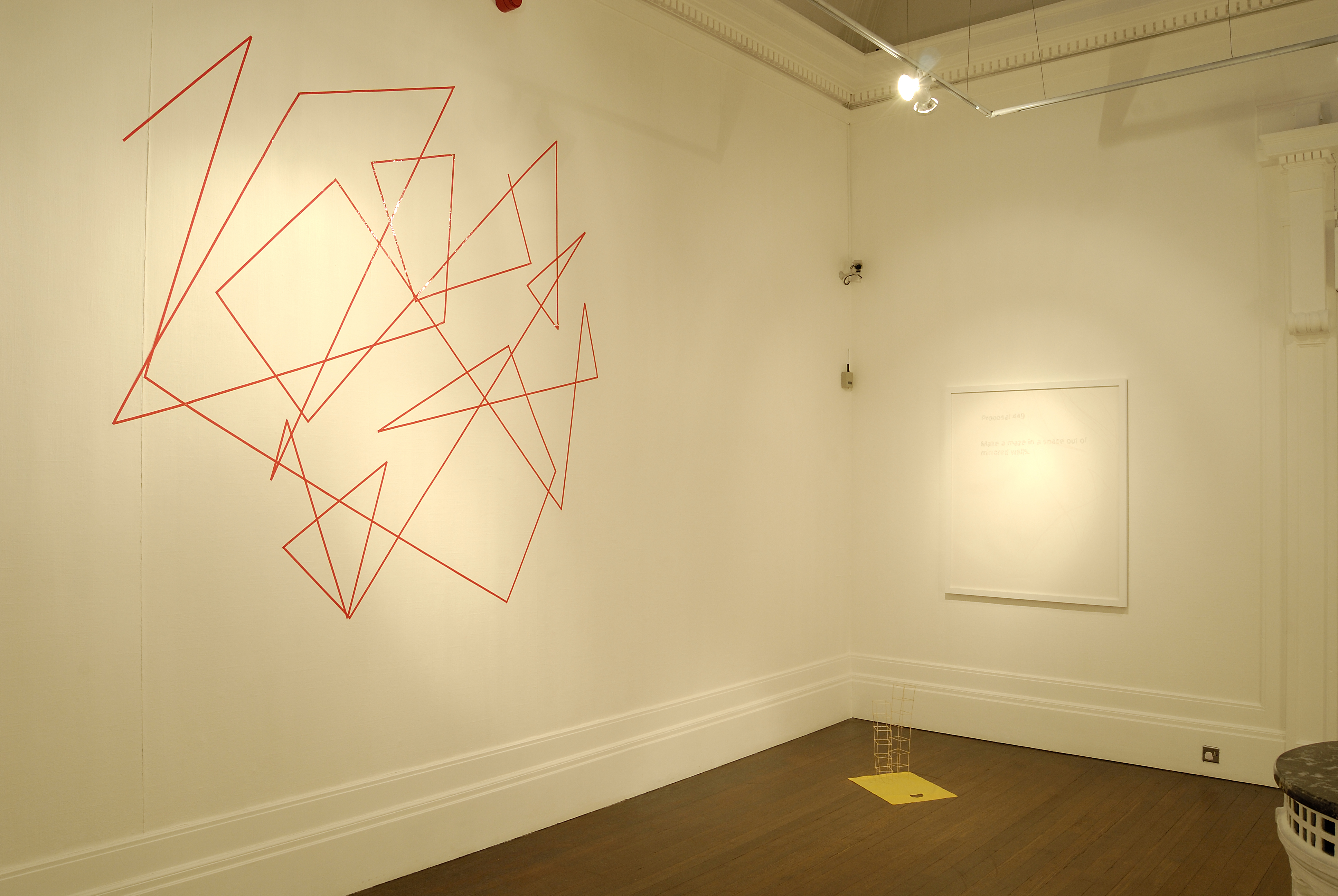 Gallery wall with wall based linear pattern. The pattern consists of red lines intersecting at sharp angles. The artworks is by artist Stuart Edmundson