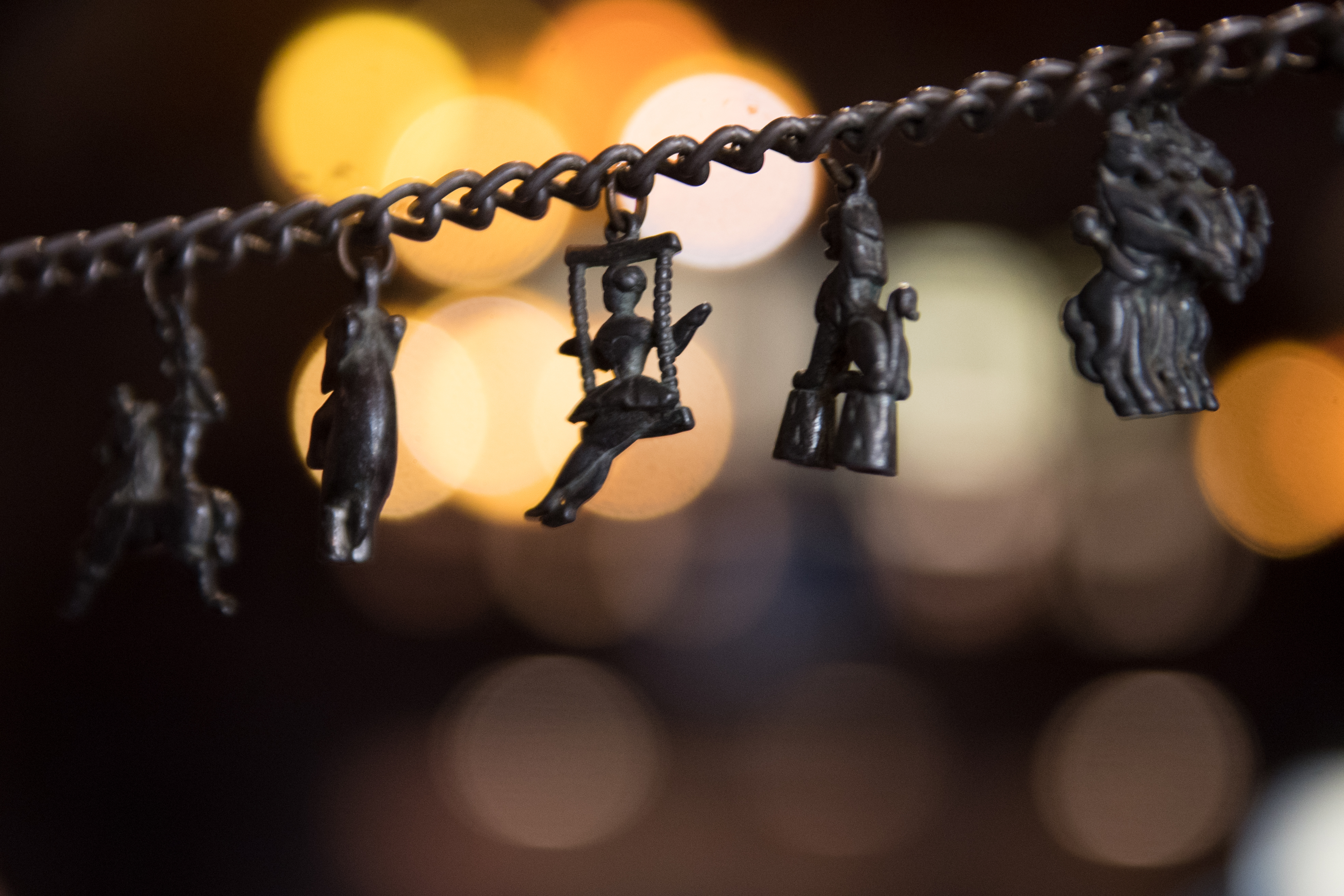 A charm bracelet. The bracelet has a variety of different circus themed performers including a lion, horse riders and trapeze swing artist. Photograph included in the exhibition Retired Performers: The Interval by photographer Claire Griffiths